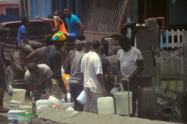 Local residents fill containers of water after a series of eruptions from La Soufriere volcano