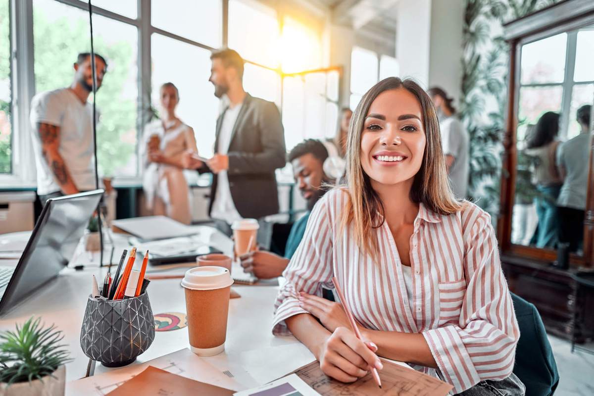 Smiling female employee sit in coworking space and working on the project