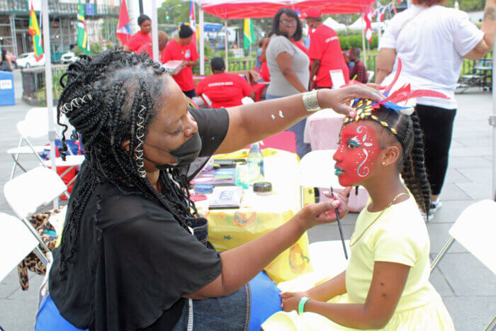 “Kids I Adore” artist, Deloris “Nzingha” Thompson painting the face of a little girl at the Caribbean Heritage Month festivities on Brooklyn Borough Hall Plaza.