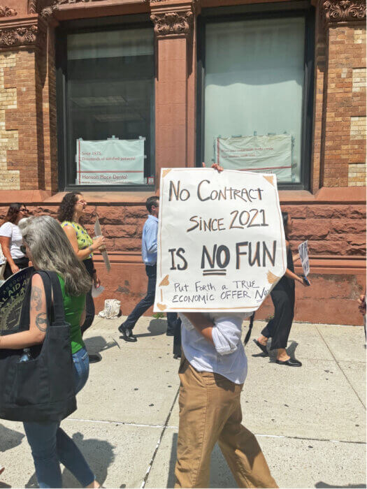 A protestor with a sign that shows how tired BDS employees are of having no contract since unionizing in 2021.