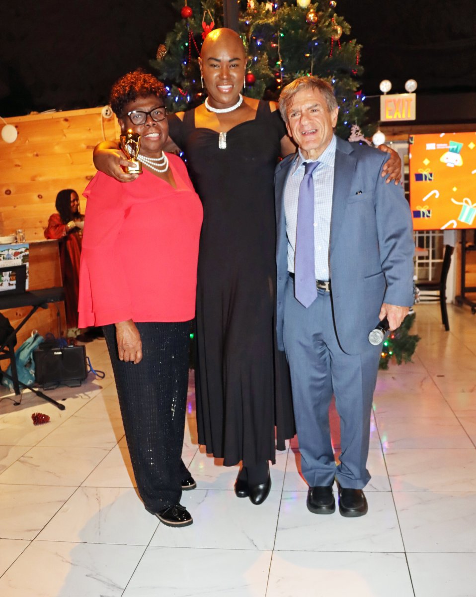 Kamla Millwood, center, holds award, with Jean Joseph and MC Lion Benjamin M. Pinczewski, Esq.