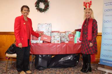 Trinidadians Jean Alexander, left, and Dolly L. Williams pose with wrapped gifts to be distributed.