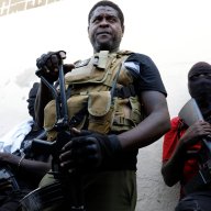Barbecue, the leader of the "G9 and Family" gang, stands with his fellow gang members after speaking to journalists in the Delmas 6 neighborhood of Port-au-Prince in Port-au-Prince, Haiti, Tuesday, March 5, 2024. Haiti's latest violence began with a direct challenge from the former elite police officer Jimmy Chérizier, known as Barbecue, who said he would target government ministers to prevent the prime minister's return and force his resignation.