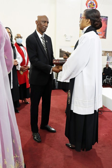 Pastor the Rev. Dr. Roxie Morris's husband, Stanley Morris, presents her with a bible.