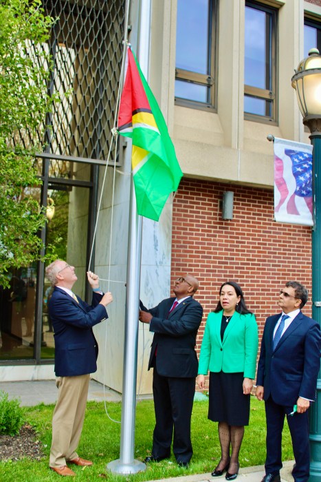 Supervisor Don Clavin, Hempstead Town Board, left, Consul General of Guyana in New York, Michael E. Brotherson, hoisting the the Golden Arrowhead flag over the Dorothy L. Goosby Park, in Hempstead Township, Long Island, to celebrate Guyana's 58th Independence Anniversary, as Permanent Representative to the UN, Carolyn Rodrigues Birkett, and Advisor on Investment & Diaspora Affairs Fazal Joe Yussuff, look on. The ceremony was held on on May 17.
