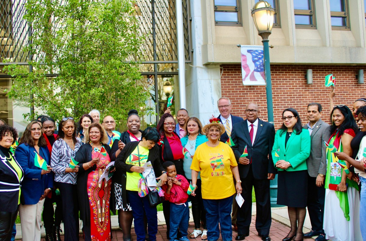A colorfully dressed group of nationals, family and friends, pose with Ambassadors Michael E. Brotherson, and Carolyn Rodrigues Birkett, Don Clavin, Trudy King, Leroy Beresford, Metro Plus Health, Clariona D. Griffith, Bibi Alli, Sherry Williams, staff of the Consulate, Mission, and others.