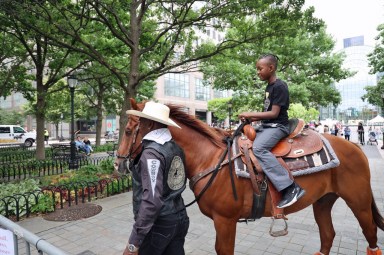 An educator from The Federation of Black Cowboys shows a cowboy-to-be how to ride on horseback.