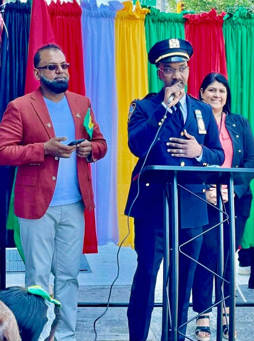 Faiuze Ali, host of Guyana Day USA, New York Chapter, left listens as Guyanese heritage, Captain Berkley VanTull, commanding officer of the 16 Precinct, Queens, addresses the audience at the 58th Independence Anniversary celebration awards hosted by the Guyana Day USA Inc. New York chapter on Liberty Avenue, Queens.