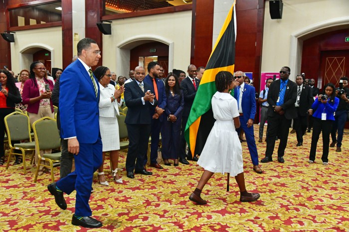 High school student marches with the Jamaican flag as Prime Minister Andrew Holness follows.
