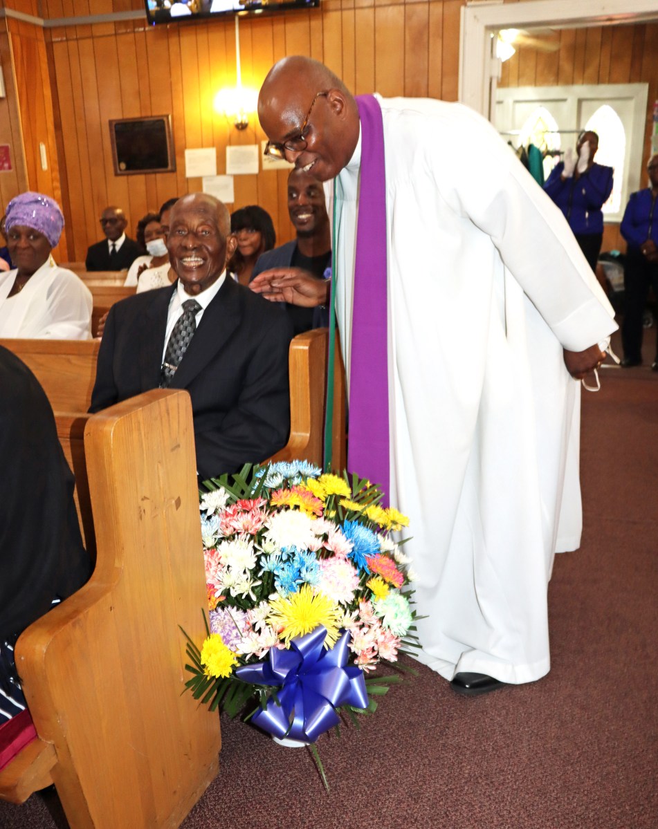 Pastor Roger Jackson after presenting a bouquet of flowers to Bro. Lester Jack, 95, the oldest member of the church.