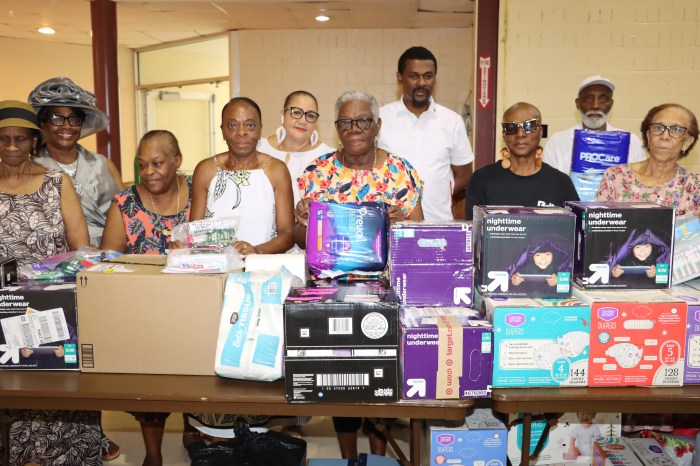 St. Vincent and the Grenadines' United States Consul General Rondy McIntosh, back row, in white shirt, without cap, with nationals, with some relief items in foreground, at the Friends of Crown Heights Educational Center in Brooklyn