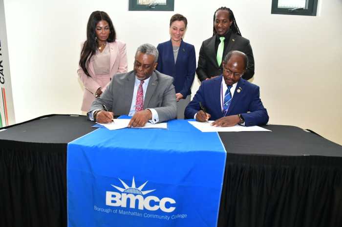 BMCC President Dr. Anthony E. Munroe, left, signs agreement with Prof. Colin Gyles, CD, UCC president, flanked by officials