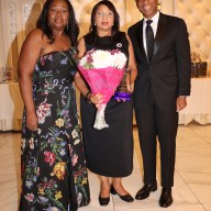 Michelle Stoddart, center, receives award and bouquet of flowers from Justice Sylvia Hinds-Radix and Rudyard Whyte, Esq.
