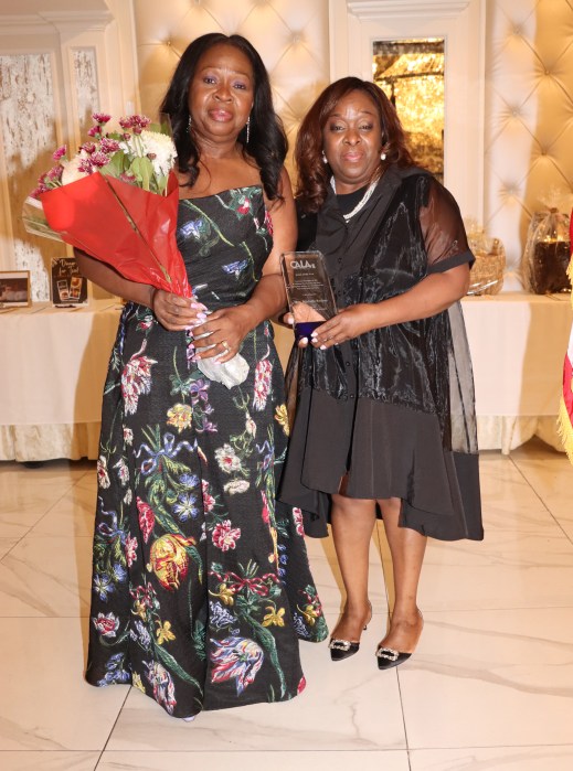 Justice Michele S. Rodney receives award, and Justice Sylvia Hinds-Radix, left, holds bouquet of flowers for her.