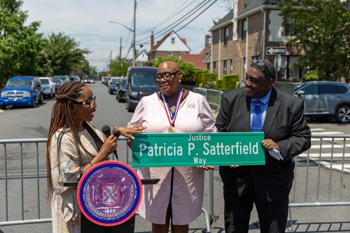 Dr. Danielle N. Williams and her husband, Allen David Williams, Sr., hold street co-naming sign while speaking with a reporter.