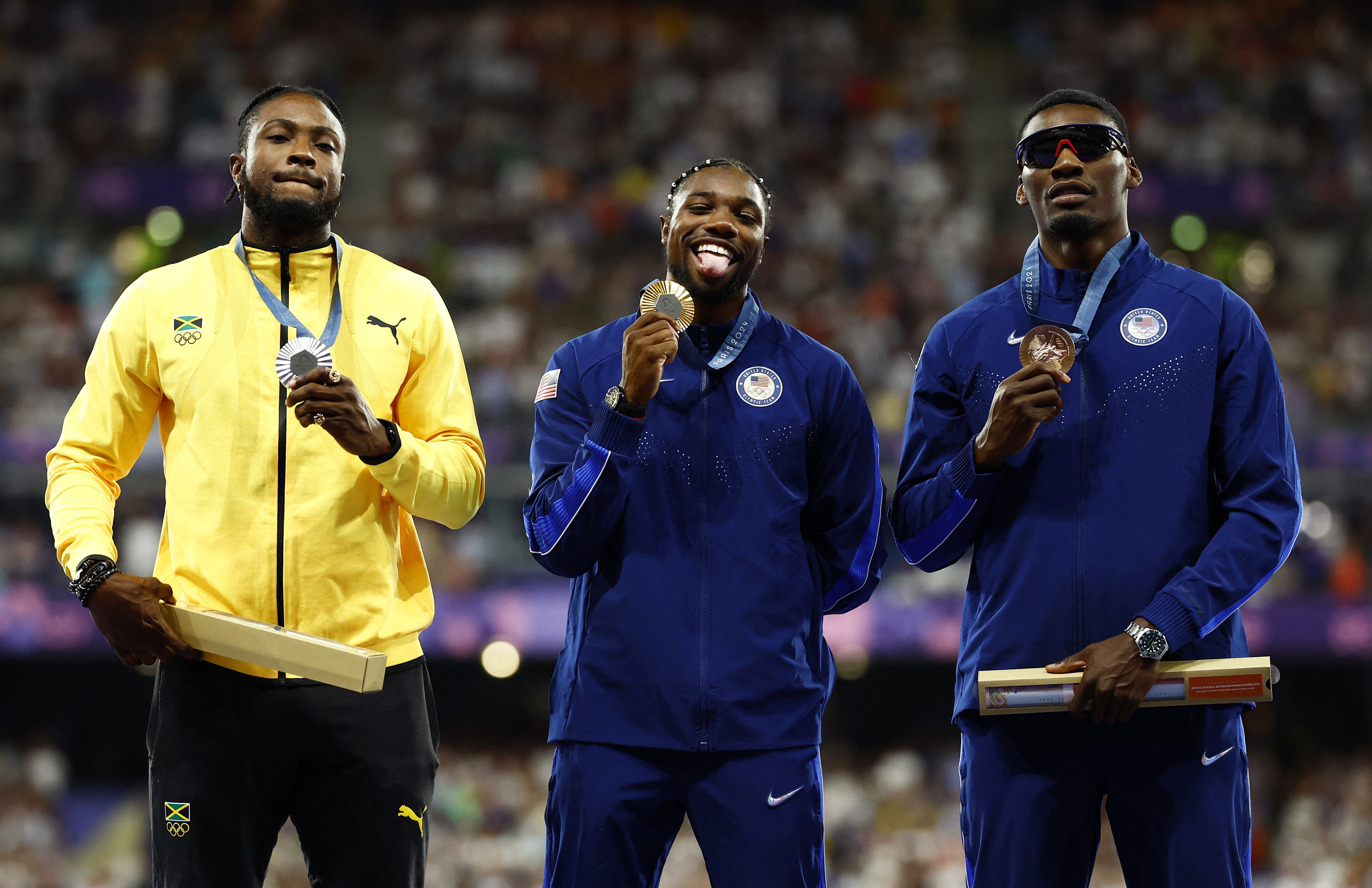 Gold medallist Noah Lyles of United States celebrates on the podium with silver medallist Kishane Thompson of Jamaica and bronze medallist Fred Kerley of United States.