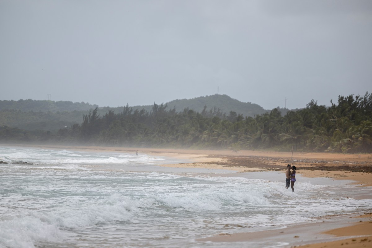 A couple kisses on a beach as Tropical Storm Ernesto approaches Luquillo, Puerto Rico August 13, 2024.