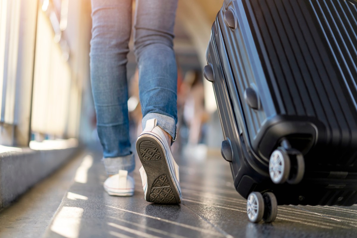 Woman traveler walking alone with suitcase bag. Travel weekend vacation trip.