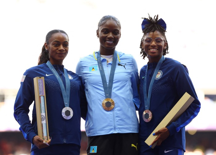 Paris 2024 Olympics - Athletics - Women's 100m Victory Ceremony - Stade de France, Saint-Denis, France - August 04, 2024. Gold medallist Julien Alfred of Saint Lucia celebrates on the podium with silver medallist Sha'carri Richardson of United States and bronze medallist Melissa Jefferson of United States.