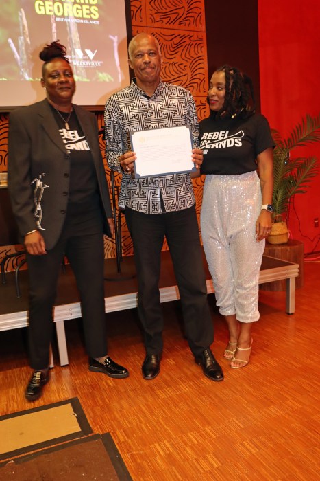 Sir Hilary shows citation from NYC Mayor Eric Adams, flanked by Marsha Massiah, right, Melany Paynter.