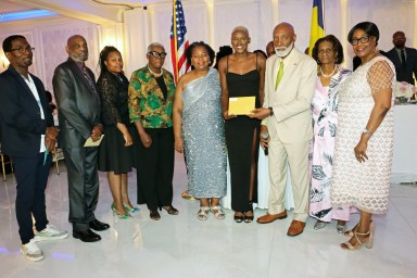 Shafiqua Maloney, fourth from right, receives a gift from Crispin Friday, president of the St. Vincent and the Grenadines Organizations, USA, Inc. (COSAGO), flanked by members of the St. Vincent and the Grenadines Nurses Association, Mas Productions Unlimited, and Vincy Day USA Committee.