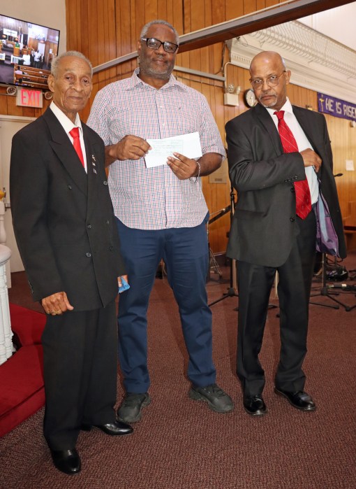 Barbadian-born Orson Harris, co-chair of the Finance Committee at Fenimore Street United Methodist Church, accepts financial contribution, on behalf of the church, from Men's Committee Treasurer Barbadian-born Norman Edwards, left, and President, Vincentian-born Shaphat Jack.