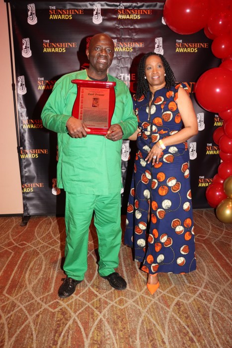 Guyanese Carl Fraser displays the award, flanked by his compatriot Allison Skeete.