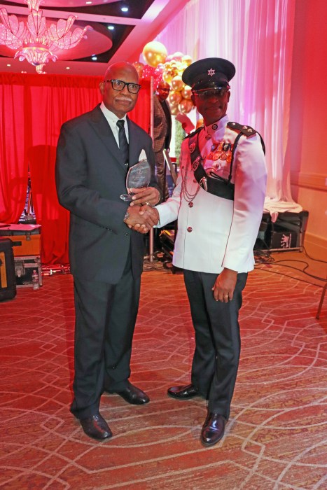 Gil Figaro, left, receives an award from Acting Superintendent of the Trinidad and Tobago Police Service Wayne Guerra.