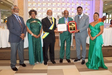 Wesley Millington, fourth from left, receives an award, flanked by COSAGO President Crispin Friday and his wife, Ancilla, to Millington's right; SVG Consul General to the United States Rondy McIntosh and his wife, Semone, to Millington's left; and O'Brien Simmons, left.