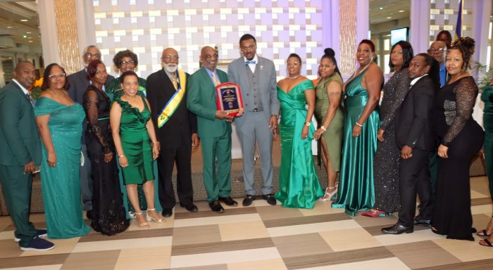 Wesley Millington, center, with plaque, flanked by COSAGO President Crispin Friday and his wife, Ancilla, to Millington's right; SVG Consul General to the United States Rondy McIntosh and his wife, Semone, to Millington's left; and members of Mas Productions Unlimited.