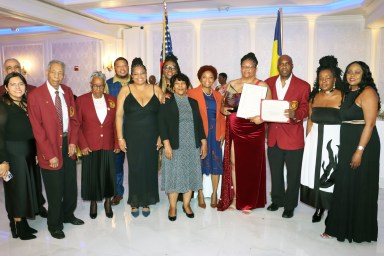 Dr. Veronica Francois-Kydd, fourth from right, receives award and proclamations, flanked by VINCI members and Council Member Mercedes Narcisse, fifth from right Narcisse, VINCI President Wayne Ragguette, third from right (holding citation), and representative of U.S. Rep. Yvette D. Clarke.