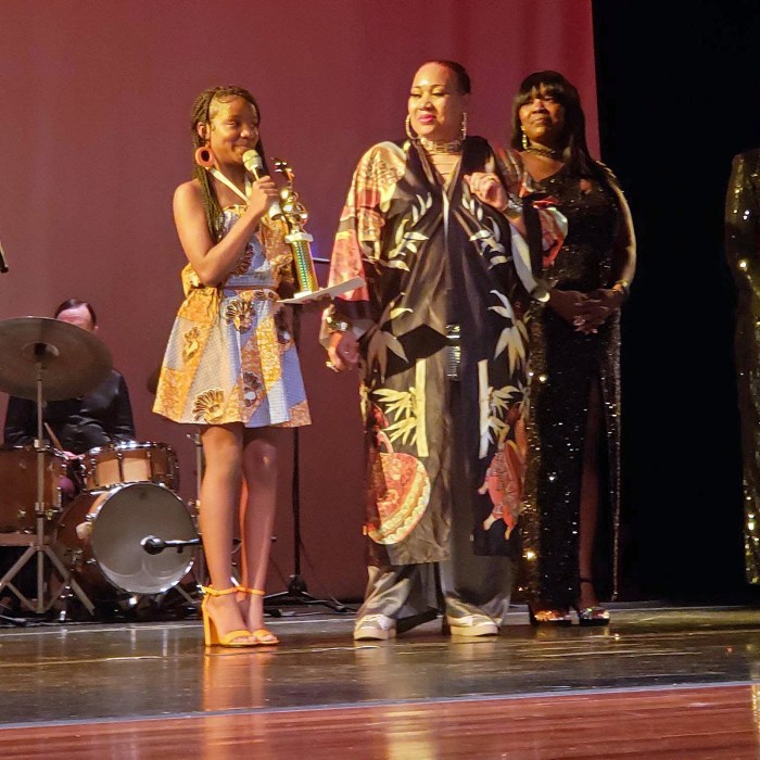 Jackie Love (J. Love Fashion School of Etiquette Inc., (center) presents an award to Amirah Holmes (Youth Designer of the Year).