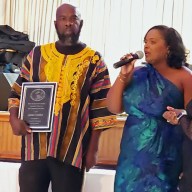 Jenell James, president of the St. Vincent and the Grenadines Association of Massachusetts, Inc., presents an award to James Cordice, a pioneer and coordinator of the St. Vincent and the Grenadines and Belize Penn Relays.