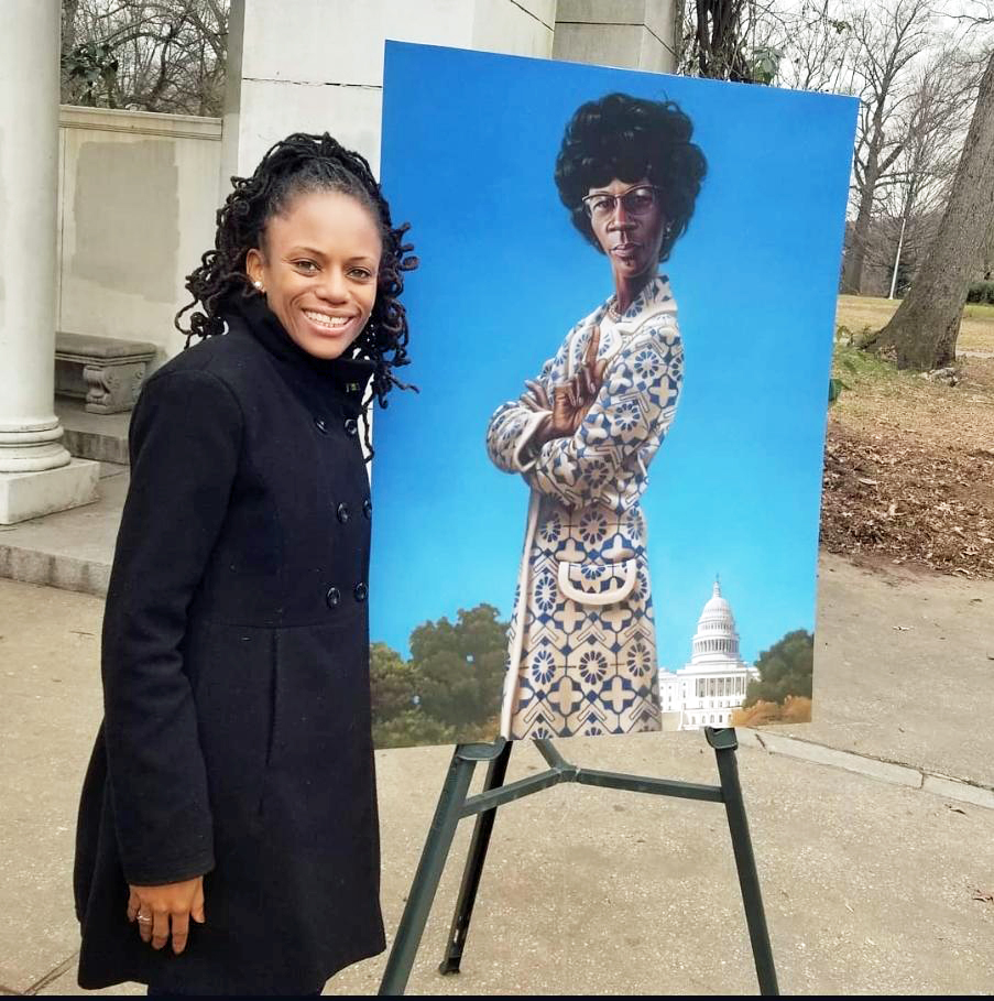 Assembly Member Monique Chandler-Waterman stands by a portrait of the late U.S. Rep. Shirley Chisholm.