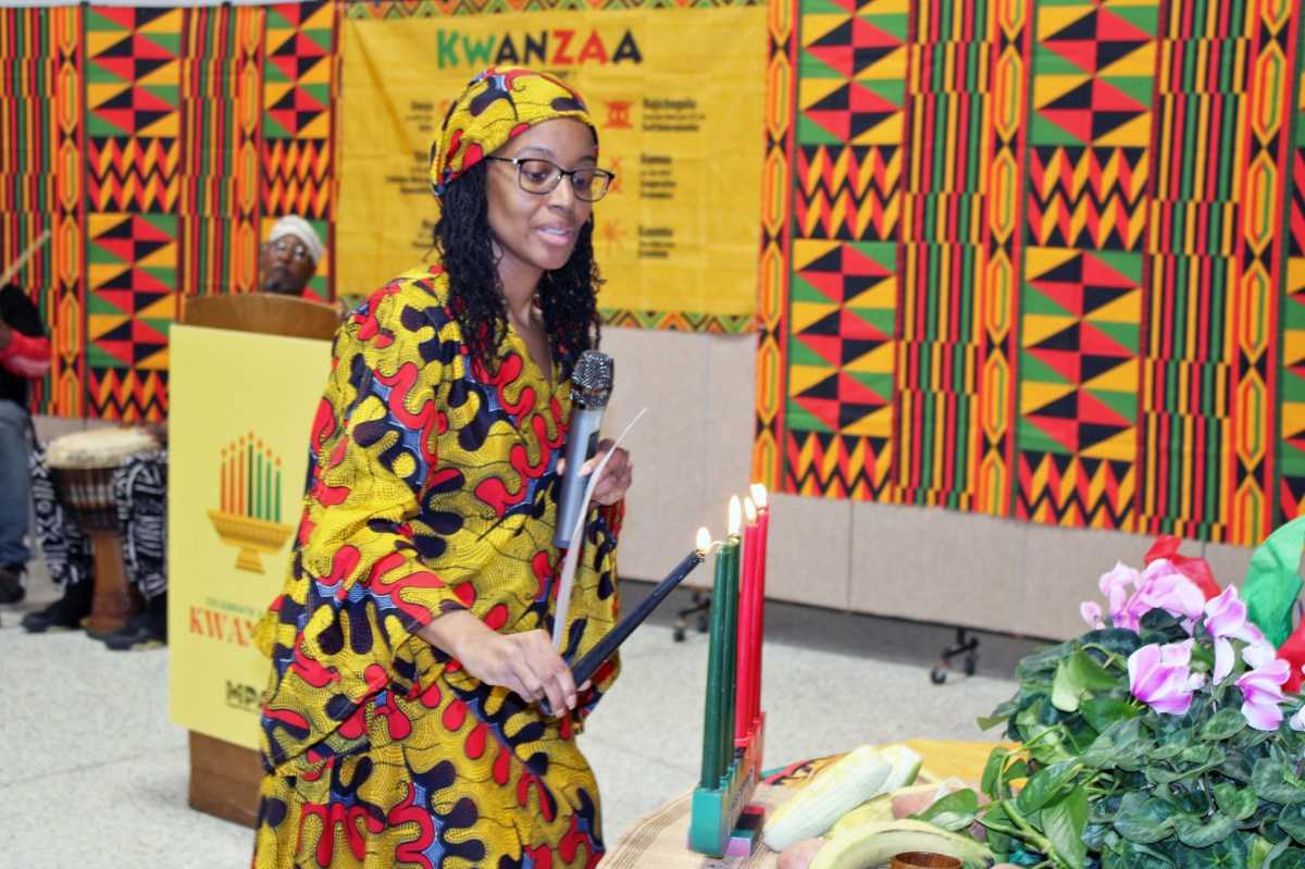 Professor Simanique Moody of Brooklyn College lights the Mishumaa Saba Candles during a pre-Kwanzaa commemoration in partnership with Marine Park Alliance and Brooklyn College, last Saturday at Carmine Carro Community Center in Brooklyn.