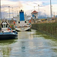 A cargo ship is seen passing through the Panama Canal, a historic passageway that accommodates thousands over many years.