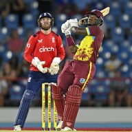 Sherfane Rutherford of the West Indies hits out for six runs watched by England wicketkeeper Phil Salt during the 4th T20 International between the West Indies and England at Daren Sammy National Cricket Stadium on November 16, 2024 in Gros Islet, Saint Lucia.