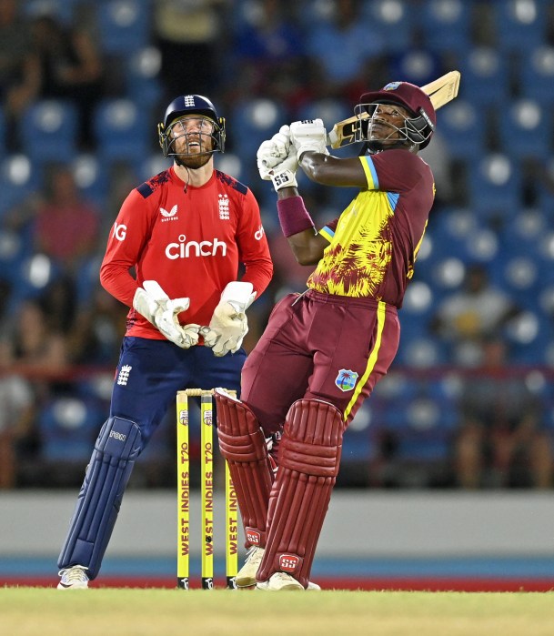 Sherfane Rutherford of the West Indies hits out for six runs watched by England wicketkeeper Phil Salt during the 4th T20 International between the West Indies and England at Daren Sammy National Cricket Stadium on November 16, 2024 in Gros Islet, Saint Lucia.