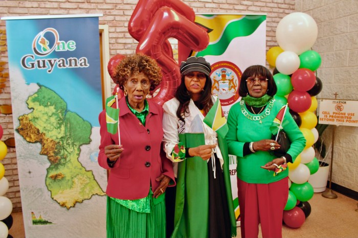 Guyanese, Norma, Bibi, and Arlene are decked out in national colors against a backdrop of the country's 55th Republic Anniversary banners of One Guyana, and Guyana Consulate during a commemoration at St. Gabriel Episcopal Church, Hawthorne St., Brooklyn, on Feb. 23.