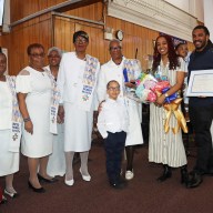 Sis. Joycelyn King, third from right, with grandson Chase King; son, Charles King, holding certificate; his wife, with bouquet of flowers; and members of Fenimore Street United Women of Faith's Special Mission Recognition Committee.