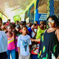 From left, fellow villager Sherif Barker, community children, and Doris Rodney after distributing school supplies during a recent mission to Soesdyke Village, Guyana.