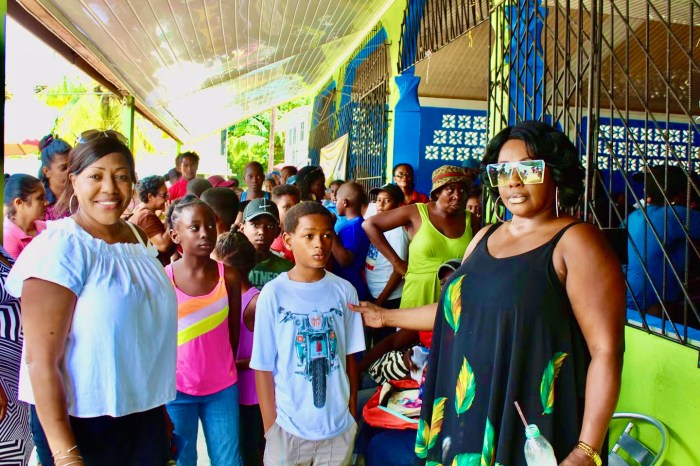 From left, fellow villager Sherif Barker, community children, and Doris Rodney after distributing school supplies during a recent mission to Soesdyke Village, Guyana.