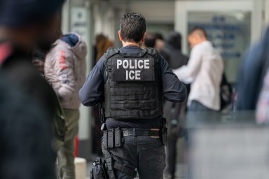 An ICE agent monitors hundreds of asylum seekers being processed upon entering the Jacob K. Javits Federal Building on June 6, 2023 in New York City.